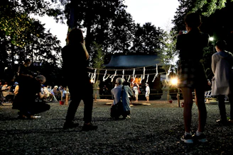 A warm gathering of diverse community members sharing stories outdoors at dusk.