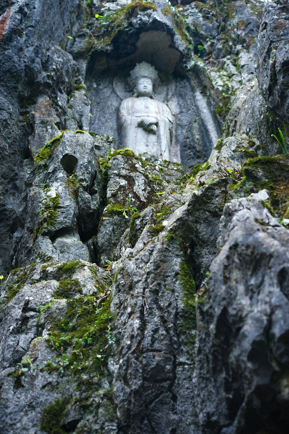 a statue of buddha in the middle of some rocks