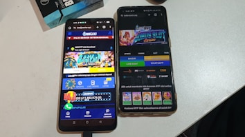 Two smartphones are displayed on a white surface, both showing gambling websites with colorful graphics, text, and various options for logging in and accessing games. The screens are bright and filled with promotional content related to casino and slot games.