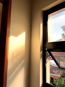 Sunlight streaming through a modern geometric window, illuminating a cozy reading nook.