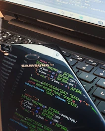 Close-up of a sleek laptop and smartphone displaying software interfaces on a desk.