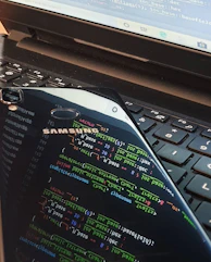 Close-up of a developer coding an Android game on a laptop with colorful graphics on screen.