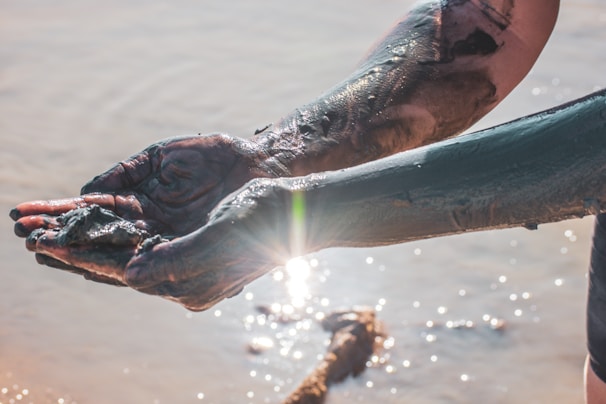 Close-up of hands in a mud therapy session.