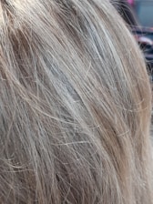 Close-up of hands applying hair fiber product on thinning hair.