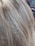 Close-up view of textured, light brown and gray hair with visible individual strands.