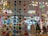 A colorful display of various hanging paper decorations, including hearts, circles, butterflies, stars, and owls. The decorations are suspended from the ceiling in multiple rows and layers, creating a vibrant and festive atmosphere. The background features a store setting with windows and shelves filled with various items.