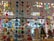 A colorful display of various hanging paper decorations, including hearts, circles, butterflies, stars, and owls. The decorations are suspended from the ceiling in multiple rows and layers, creating a vibrant and festive atmosphere. The background features a store setting with windows and shelves filled with various items.
