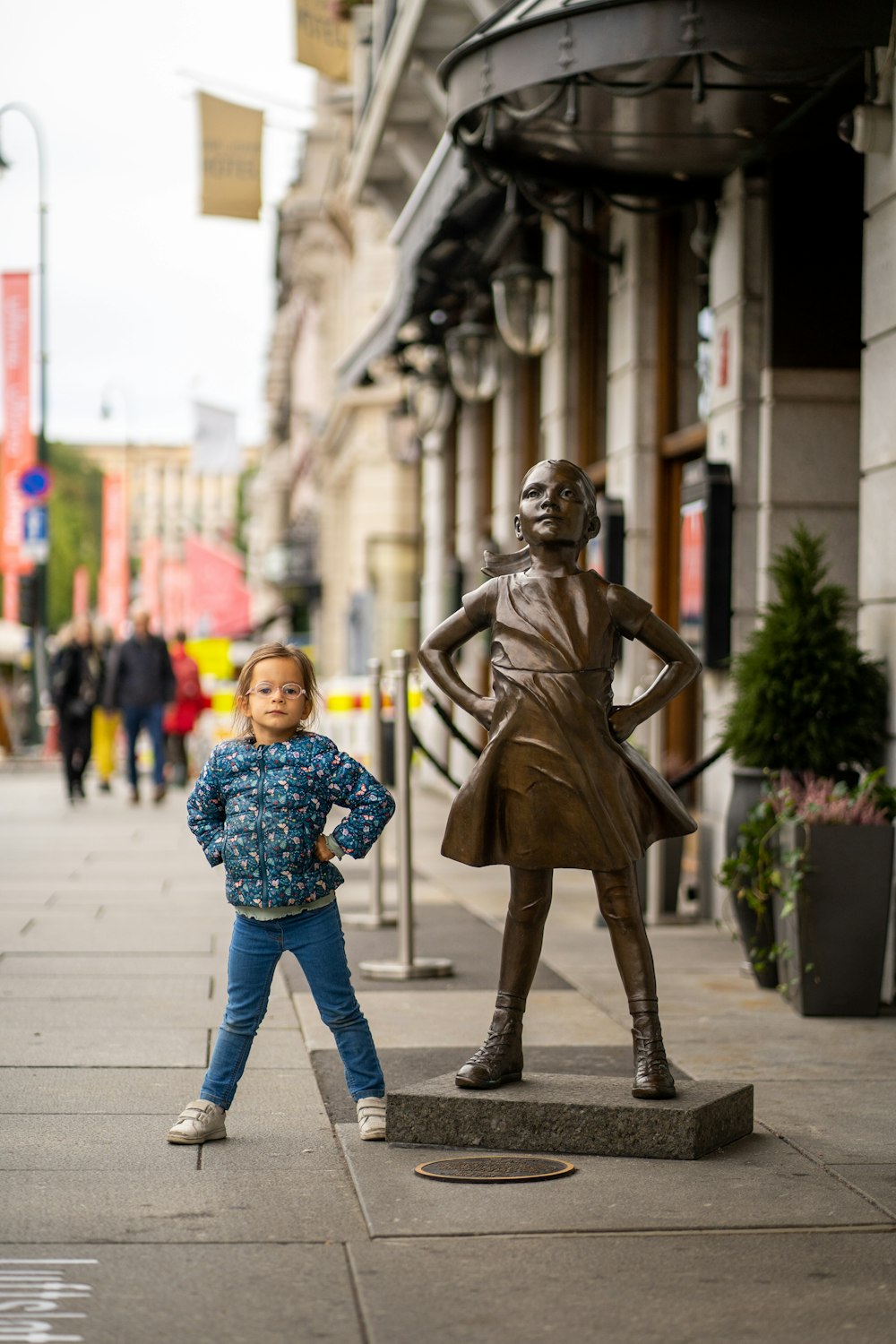 a little girl standing next to a statue of a woman