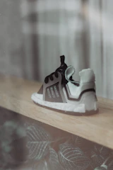 A close-up of sleek, modern sneakers resting on a minimalist wooden surface, framed by soft natural light.