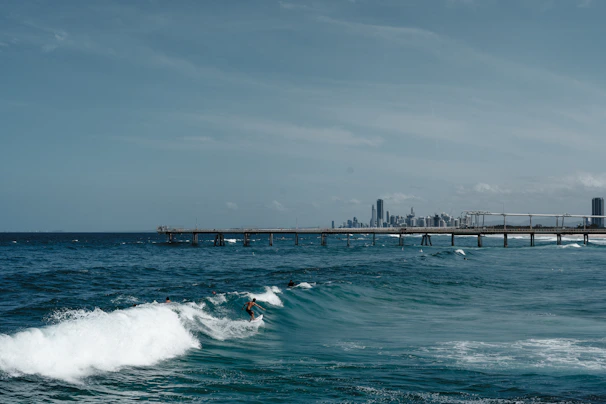 Surfers catching energetic waves under a bright blue sky near the event location