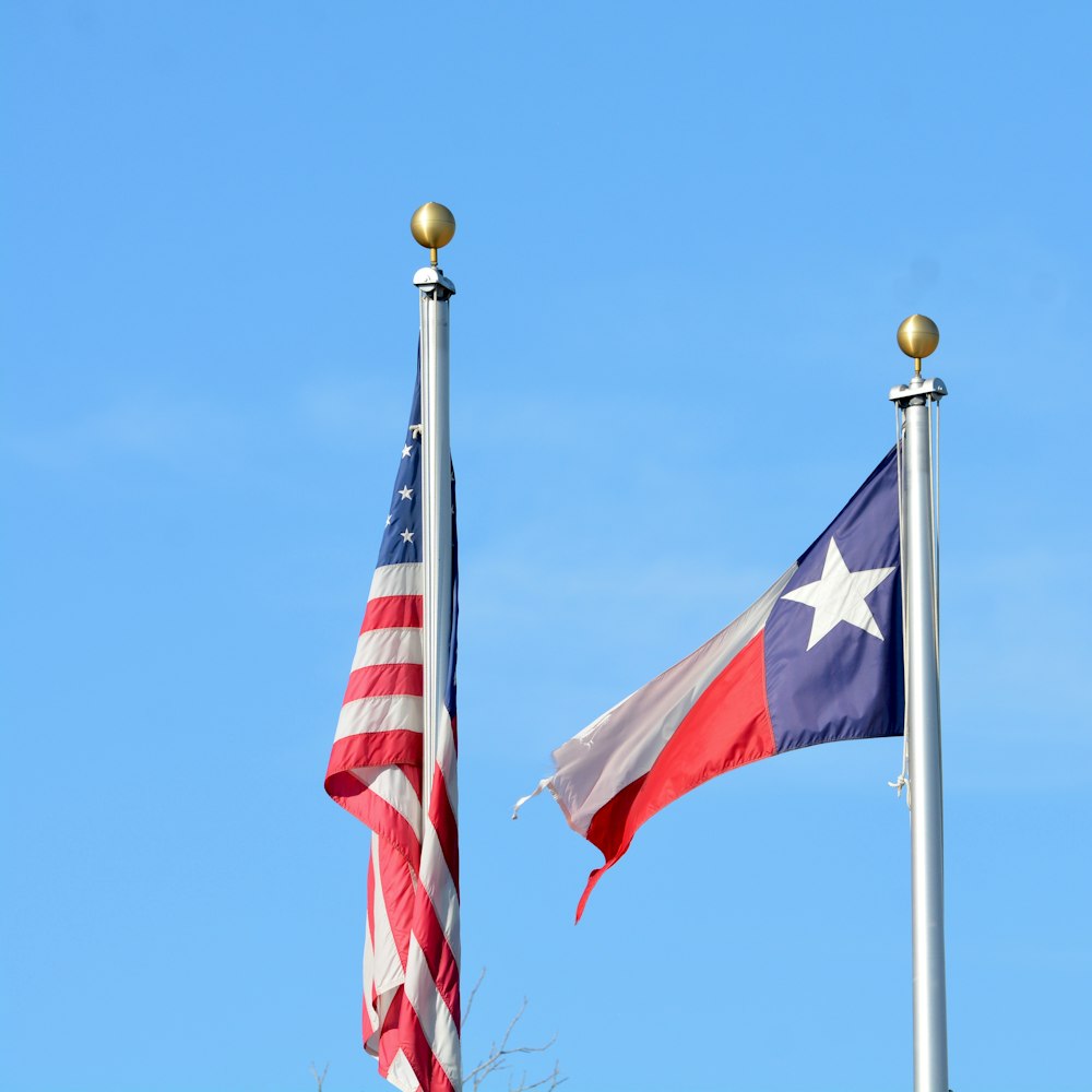 two american and texas flags flying side by side