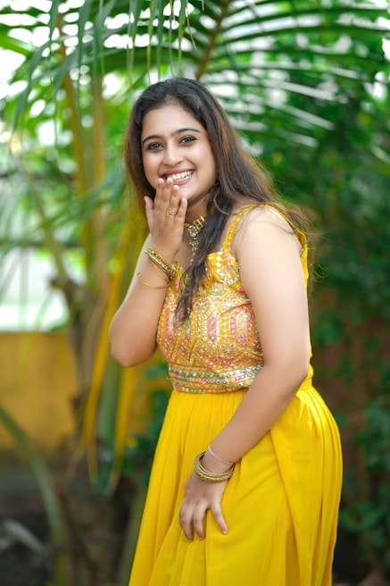 A cheerful model wearing a bright yellow kurti with intricate floral patterns