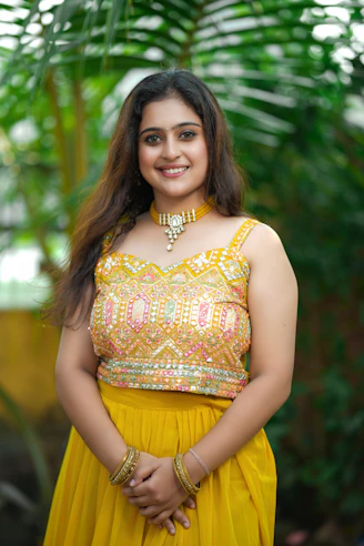 A joyful customer wearing a colorful salwar from gamani, standing in a sunlit garden.