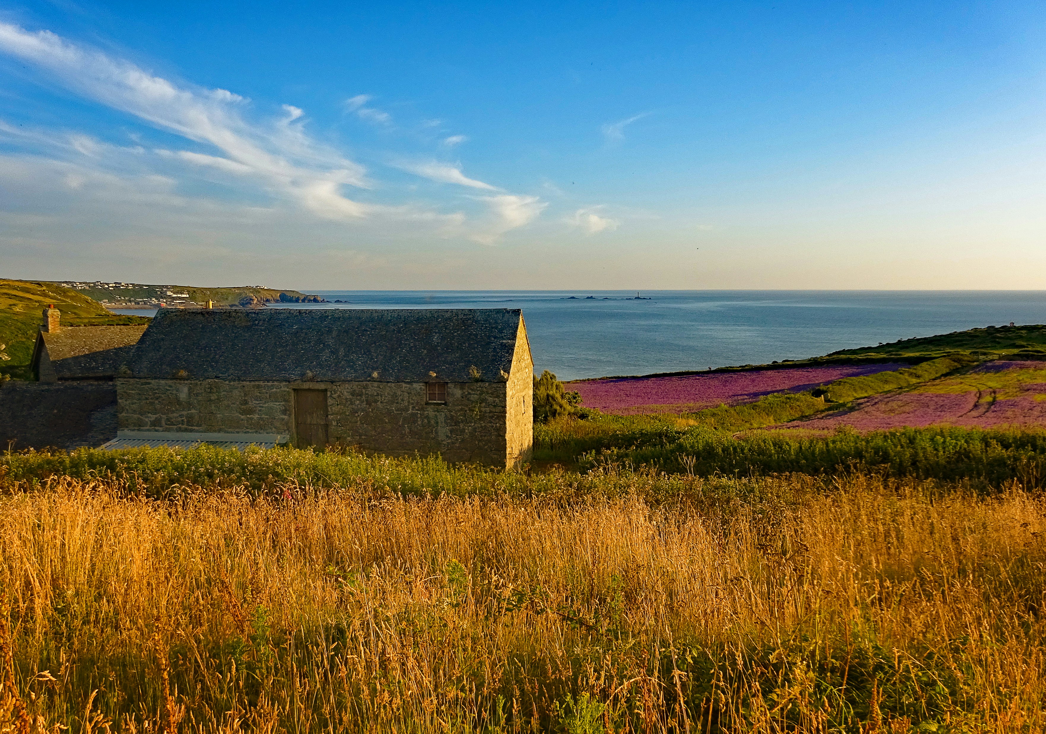 a small building sitting in a field next to a body of water