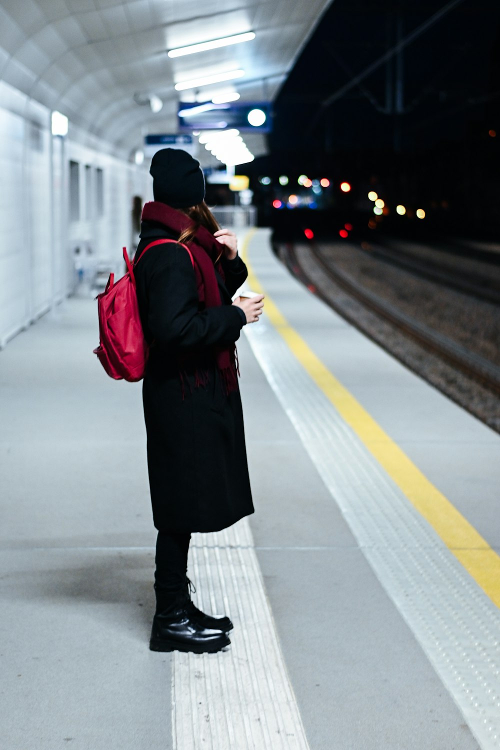a woman waiting for a train at a train station
