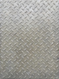A textured metal surface featuring a diamond plate pattern with raised ridges, often used for slip resistance. The surface appears worn and has a slightly tarnished appearance from frequent use.