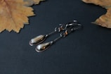Brightly polished silver earrings with antique finish displayed on a rustic wooden surface.
