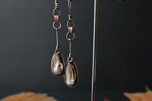 Pair of sparkling earrings hanging from a vintage jewelry stand with soft natural light