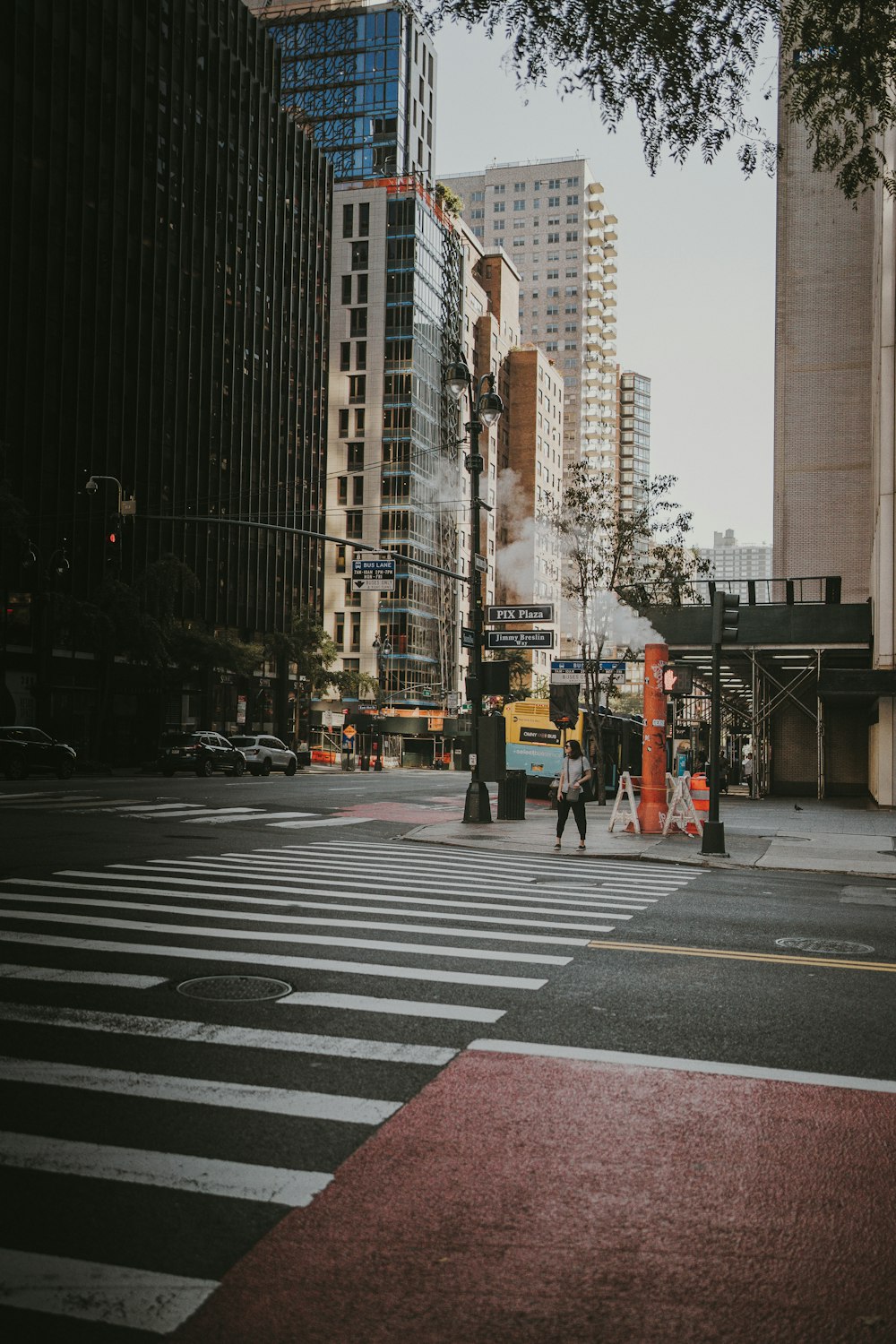 a couple of people walking across a street next to tall buildings