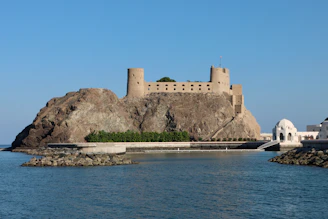 a castle sitting on top of a cliff next to a body of water
