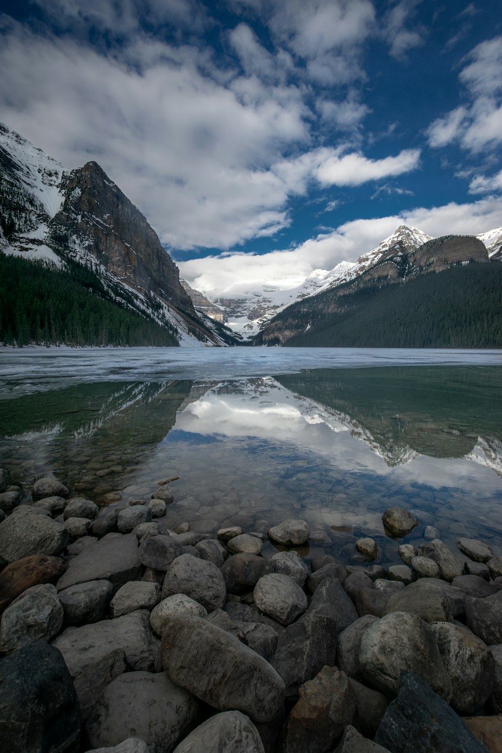 a lake surrounded by mountains under a cloudy sky