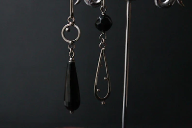 Pair of ultra-modern dangle earrings catching the light against a dark backdrop