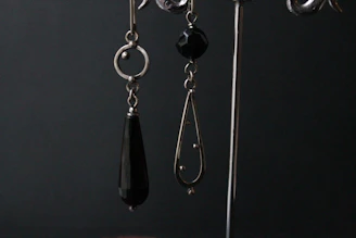 Pair of ultra-modern dangle earrings catching the light against a dark backdrop