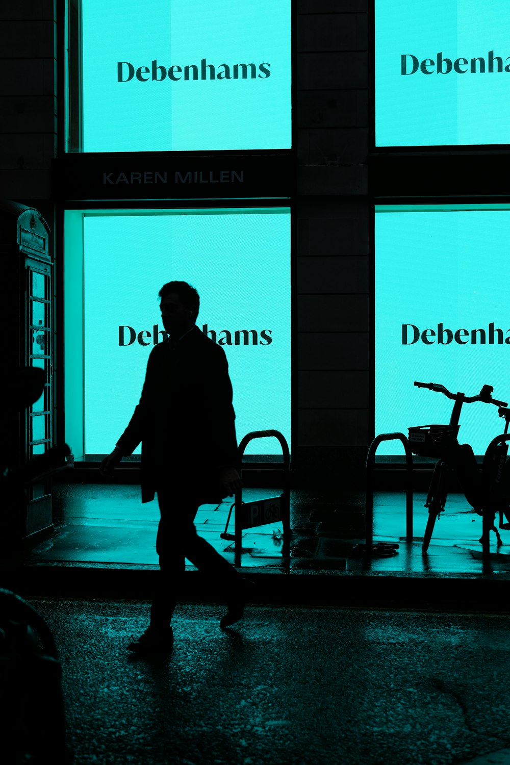 a man walking down a street past a store front