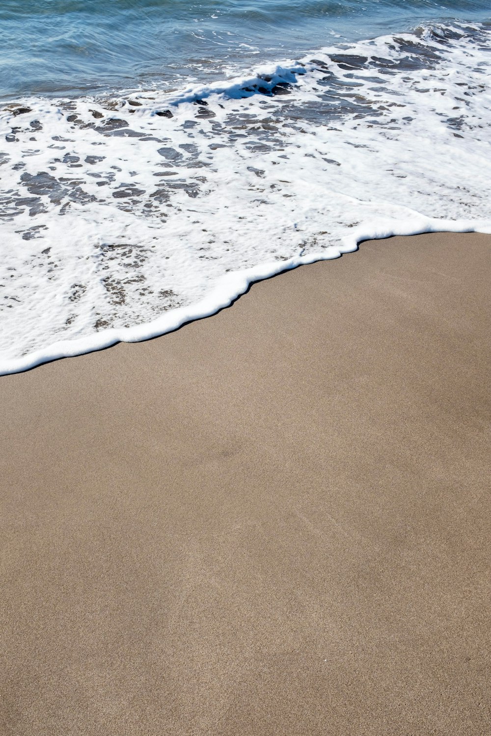 Une planche de surf est posée sur le sable d’une plage