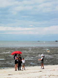 A family enjoying a beach day with umbrellas.