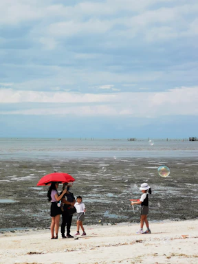 A family enjoying a beach day with umbrellas.