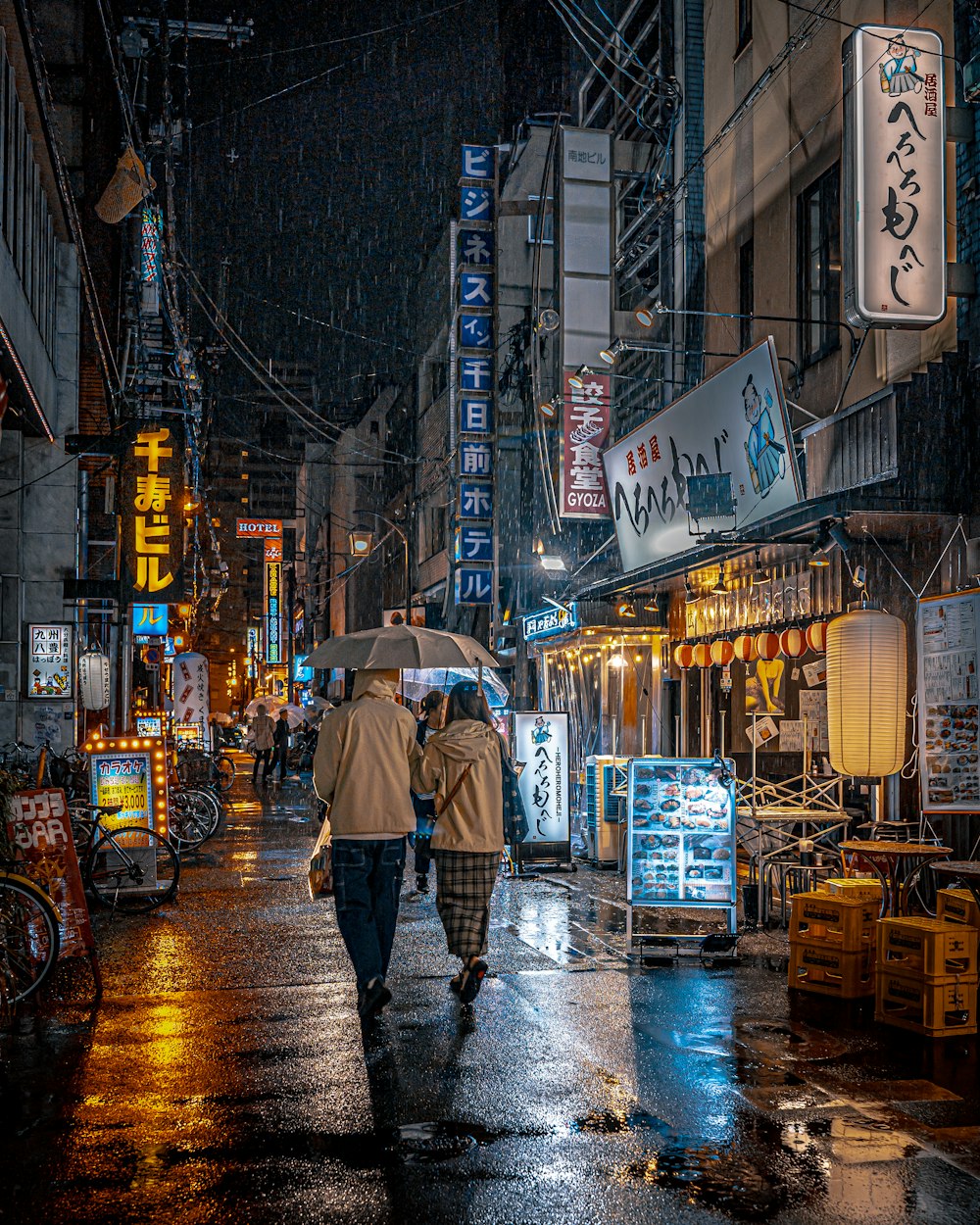 ein paar Leute, die mit Regenschirmen eine Straße entlang gehen