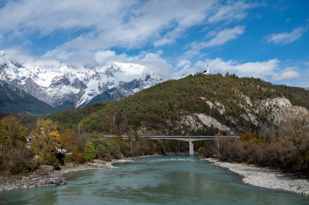 a bridge over a river with mountains in the background