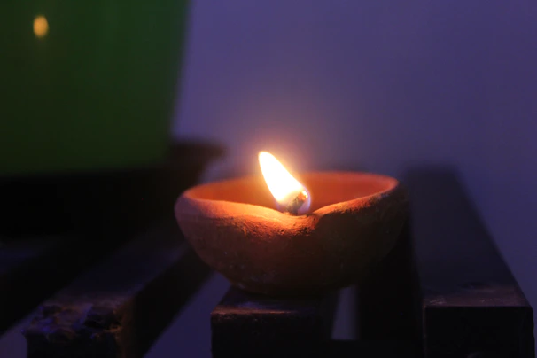 Close-up of glowing temple lamp flickering softly against a royal blue backdrop