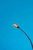 Close-up of a sleek smart streetlight glowing cyan with embedded IoT sensors against a dark urban street.