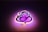 A stylized neon sign shaped like a graphical depiction of Lord Ganesha, with swirling lines and artistic curves. The sign emits a warm glow, combining shades of pink and purple, against a dark background.