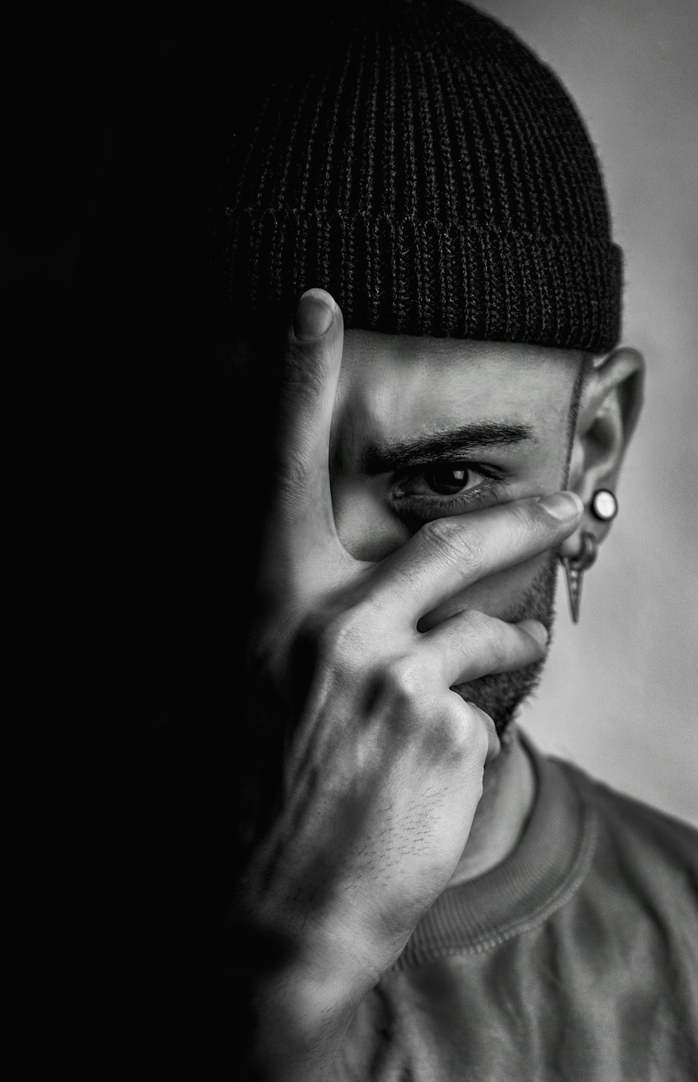 a black and white photo of a man covering his face