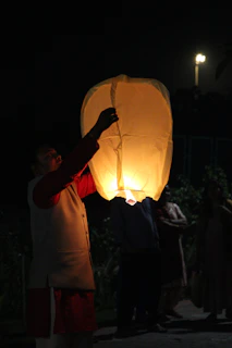 Close-up of a customer holding a glowing lantern with a joyful smile outdoors.