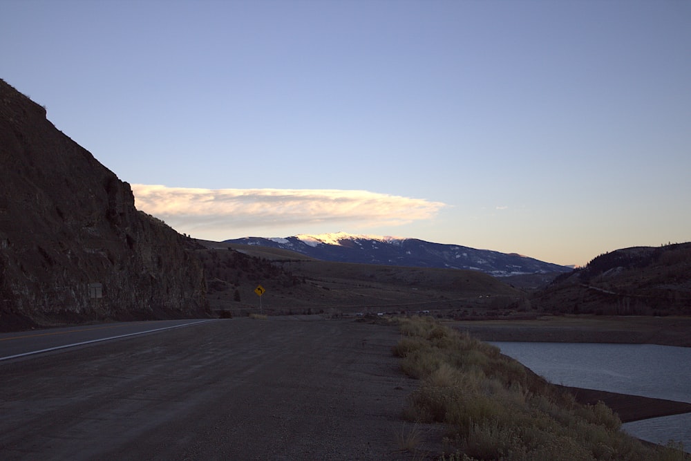 a road with mountains in the background and a body of water in the foreground