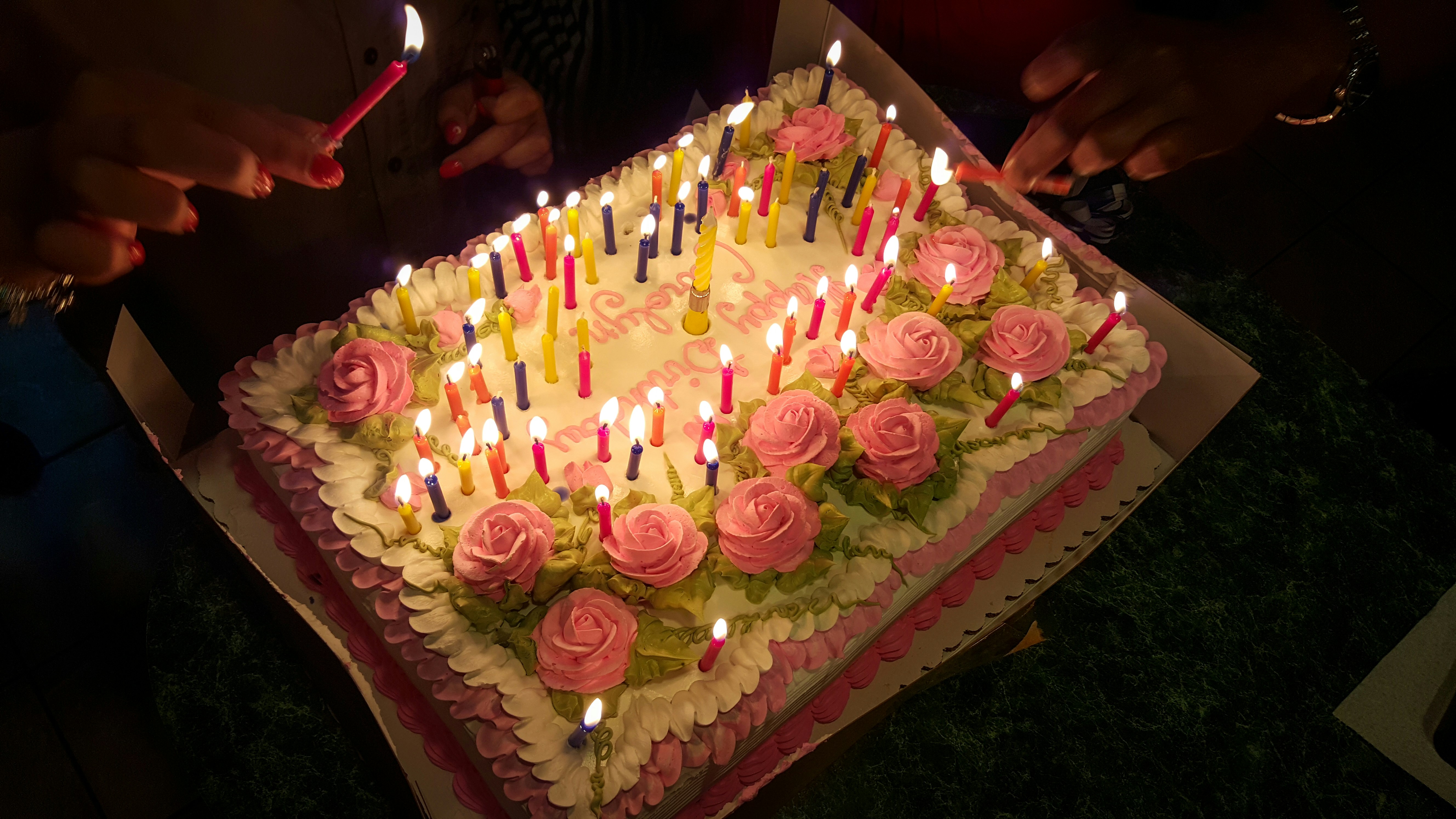 Birthday celebration preparation with colorful decorations being carefully arranged on a table in bright afternoon light