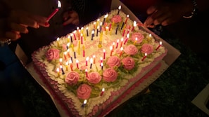 Three-layer cake candle with vibrant frosting colors and a lit wick on top