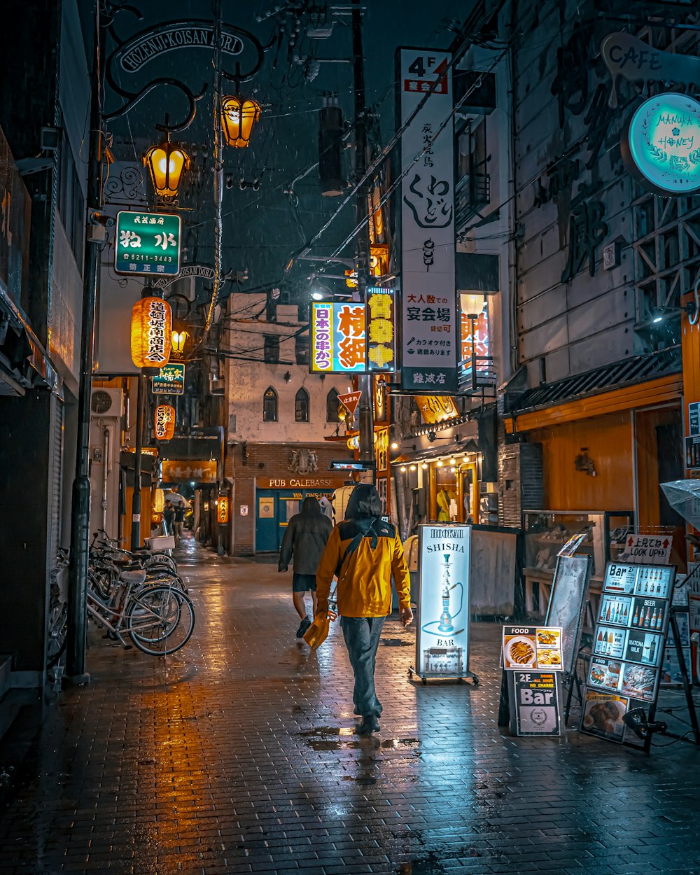 a couple of people walking down a street at night