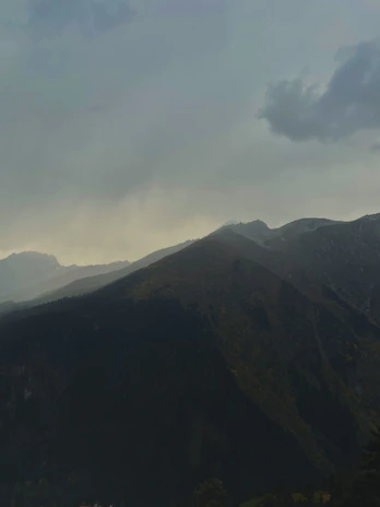 A serene landscape painting of a mountain range under a cloudy sky with subtle earthy tones.