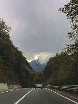 A luxury car cruising along a scenic mountain highway in Uttarakhand.