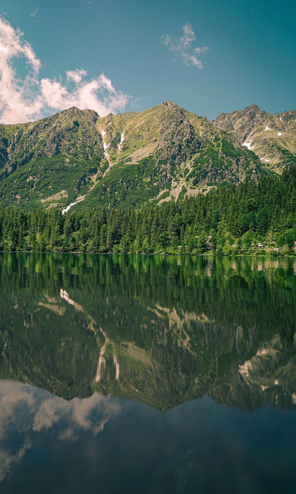 Ein Gebirgszug spiegelt sich im stillen Wasser eines Sees