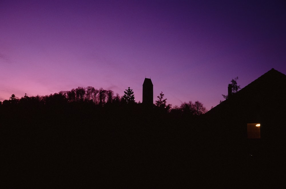 a purple sky with a clock tower in the distance