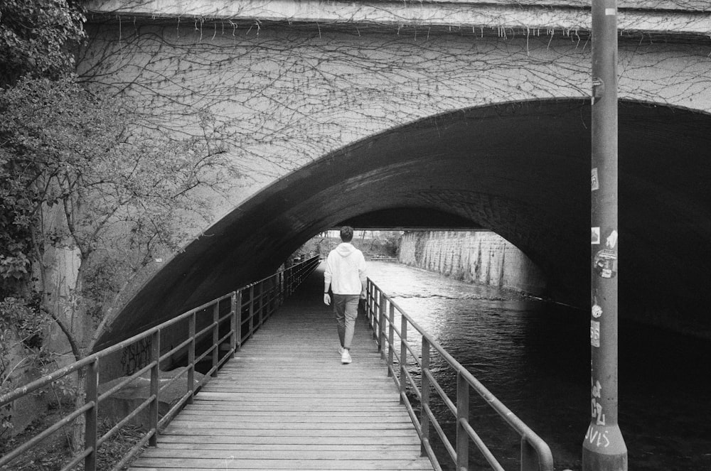 a man walking across a bridge over a river