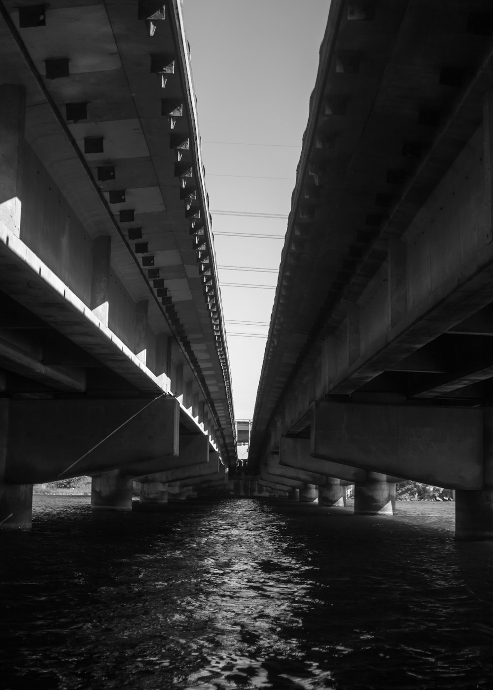 a black and white photo of a bridge over water