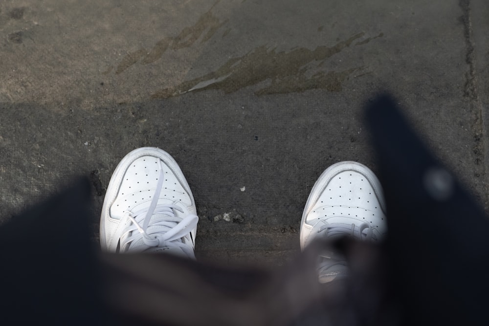 a person's feet in white tennis shoes