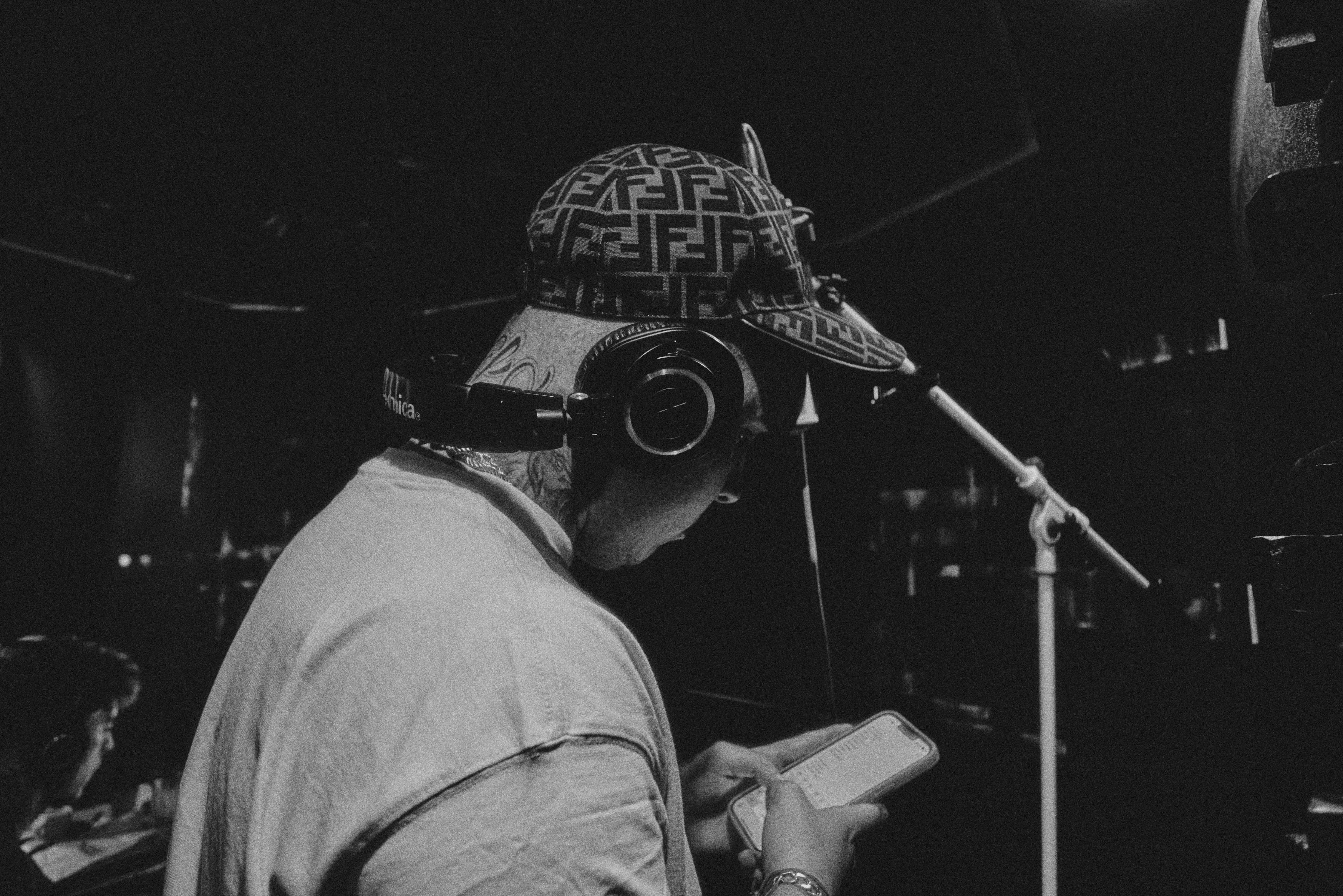 A man, wearing headphones in a recording studio wants music royalties explained to him, so he researches the different types of music licenses on his phone.